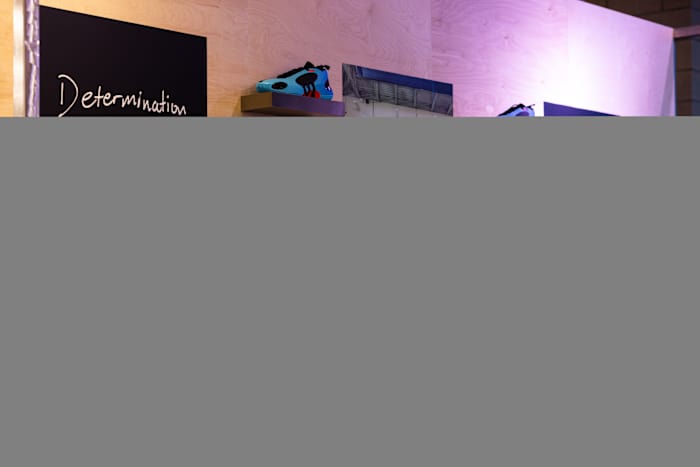 Donovan Mitchell's blue adidas sneakers line the wall at an event.